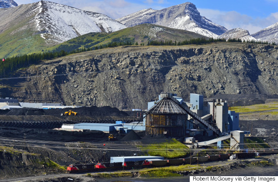 A horizontal landscape image of the Teck coal processing plant in the foothills of the rocky mountains near Cadomine Alberta, with a C.N. freight train leaving the plant loaded with coal