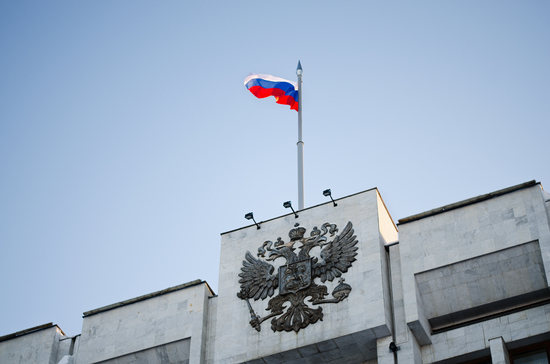 National emblem Russian Federation and flag of the Russian Federation on roof of building